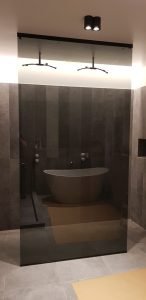 Pilkas dušo atitvaras su juoda furnitūra