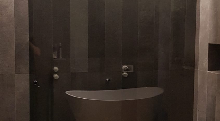 Pilkas dušo atitvaras su juoda furnitūra